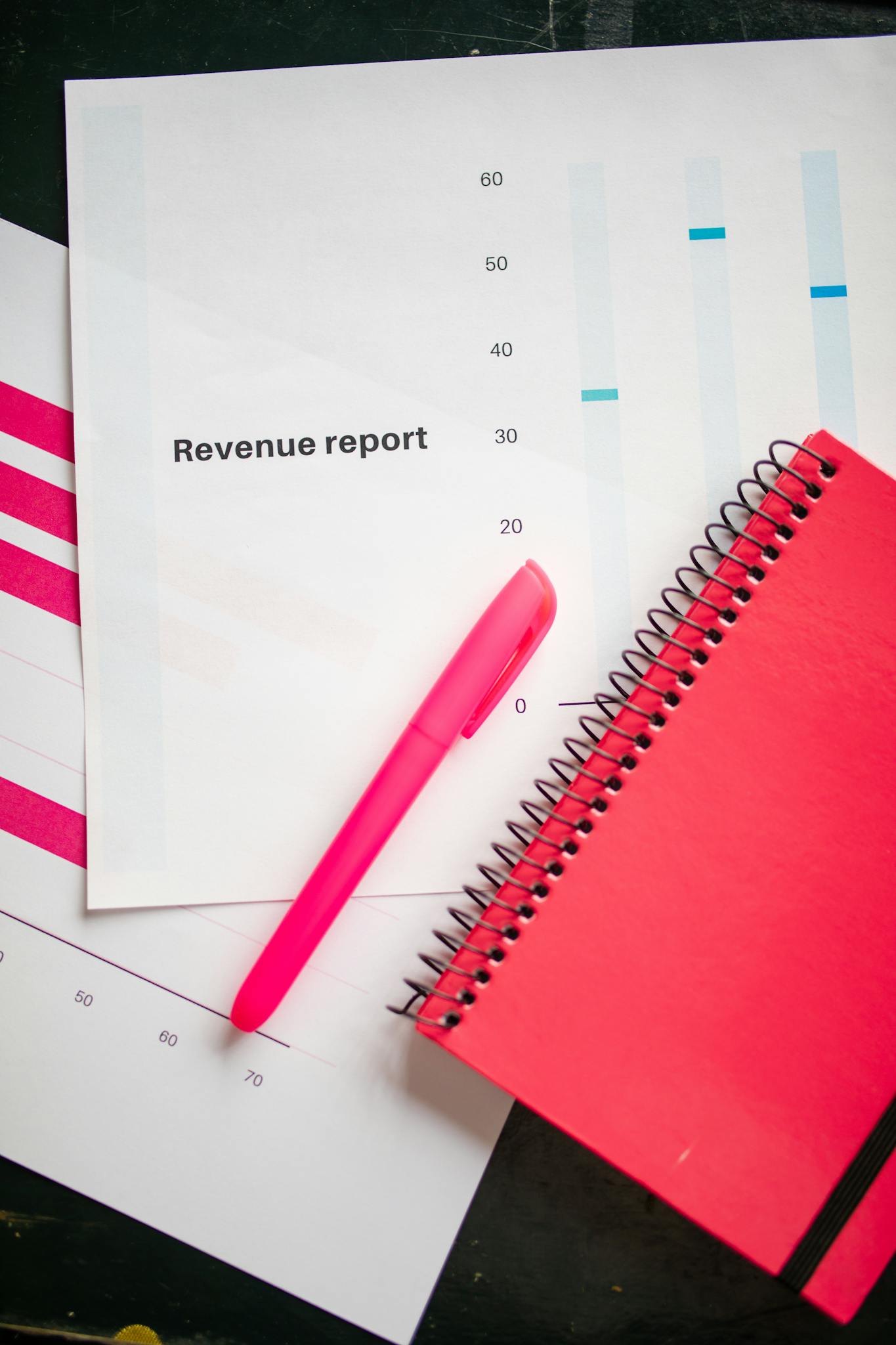 Revenue report with a pink notebook and pen on a bright flatlay, perfect for business presentations.
